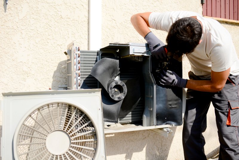 HVAC technician repairing outdoor air conditioning condenser unit
