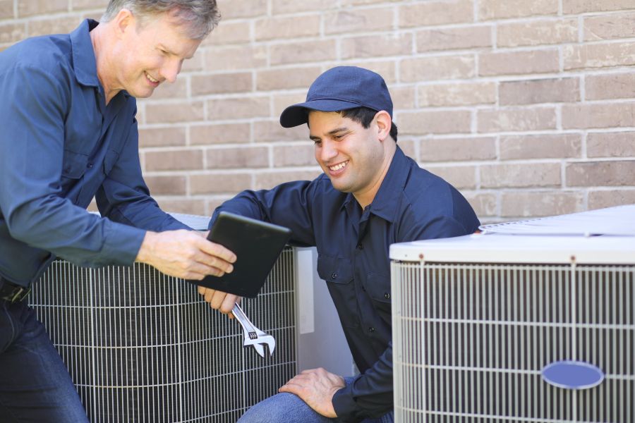 HVAC technicians inspecting and servicing residential air conditioning units in McHenry County, IL